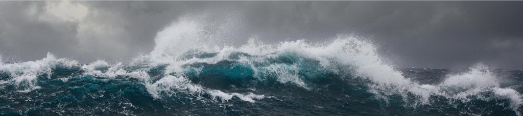 A dramatic view of powerful ocean waves crashing against each other under a stormy sky.