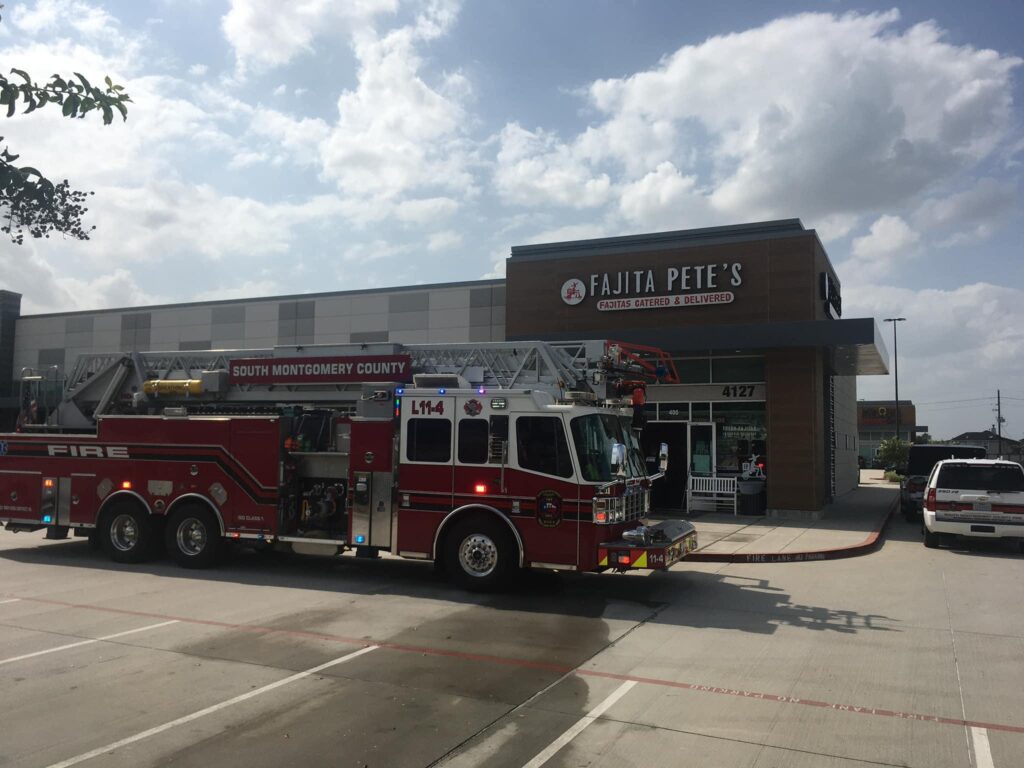 A fire truck is parked outside a restaurant named Fajita Petes in a sunny parking lot. Another emergency vehicle is also visible on the right. The sky is partly cloudy.