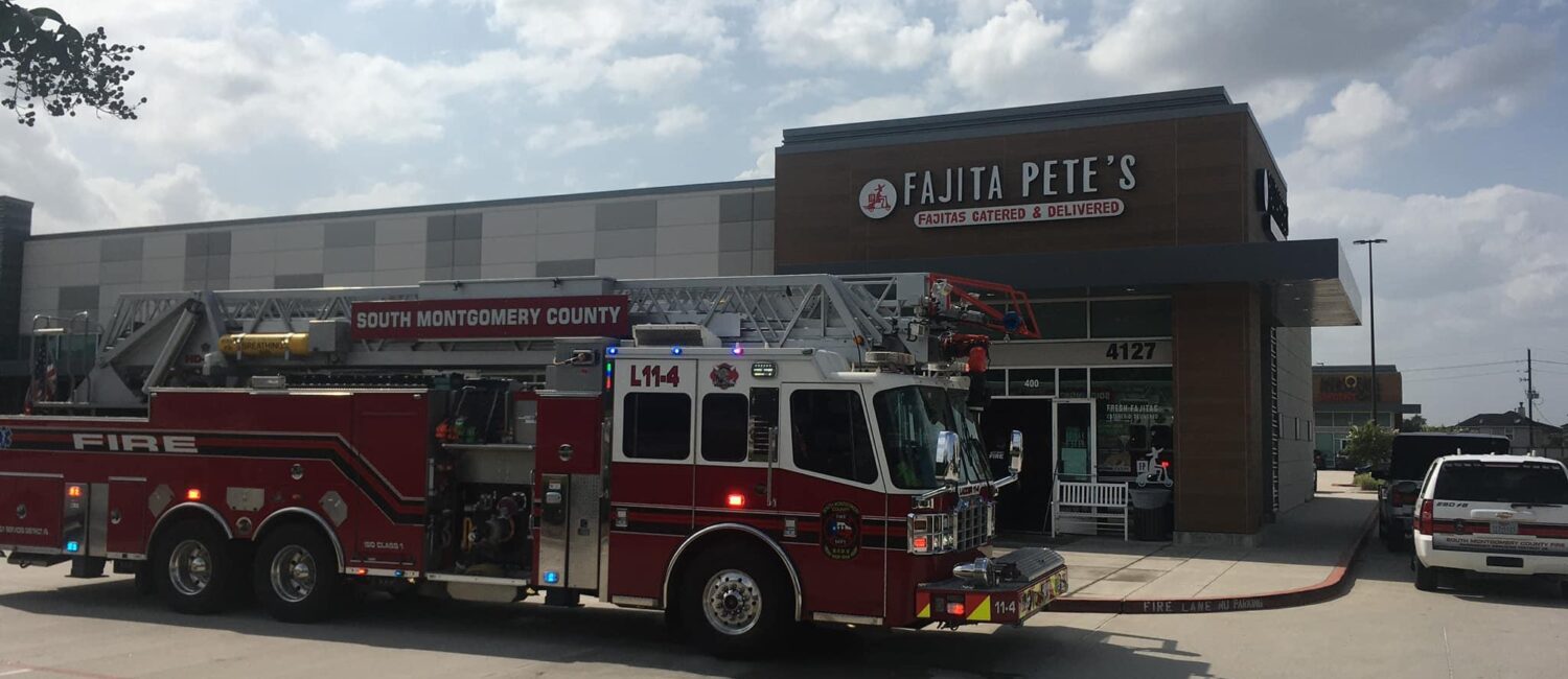 A fire truck is parked outside a restaurant named Fajita Petes in a sunny parking lot. Another emergency vehicle is also visible on the right. The sky is partly cloudy.