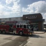 A fire truck is parked outside a restaurant named Fajita Petes in a sunny parking lot. Another emergency vehicle is also visible on the right. The sky is partly cloudy.
